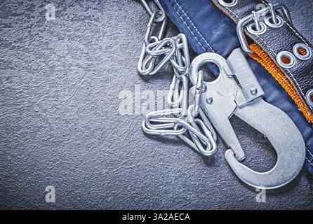 Safety strap with metal chain carabiners on black background directly above construction concept Stock Photo