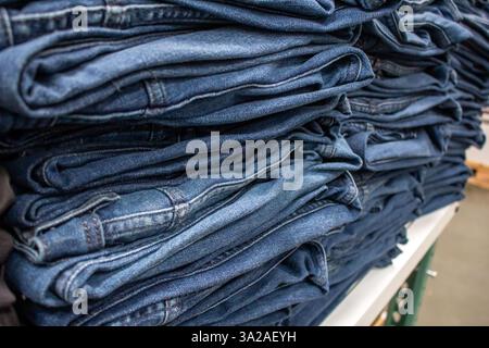 A view of several folded pairs of jeans or denim pants on a table at a department store. Stock Photo