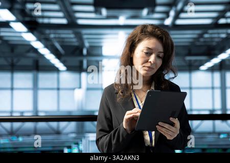 Technician in data center using tablet, conducting security audits, reviewing firewall rules, enforcing cybersecurity protocols, mitigating potential vulnerabilities, logging incident details Stock Photo