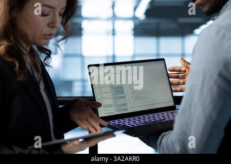 Software developers in data center workspace use laptop to calibrate energy usage. Server room IT professionals code on notebook, doing maintenance on equipment mainframes Stock Photo