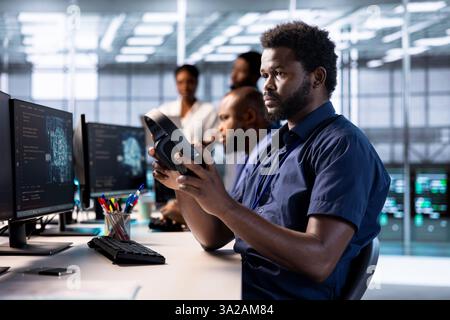 Server farm admin putting on headphones to hear songs while using artificial intelligence tech for increased productivity. Data center worker listening music, implement AI driven solutions Stock Photo
