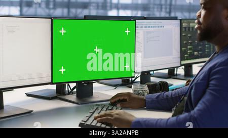 Engineer using green screen computer in server room, developing disaster recovery plans ensuring minimal downtime. Data center worker looking at mockup PC, monitoring performance, camera A Stock Photo