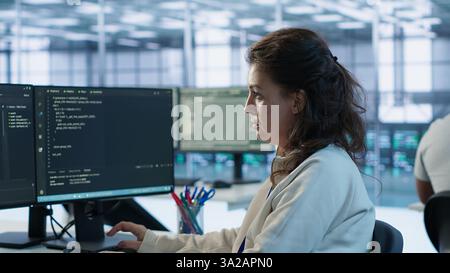 Portrait of smiling technician programming in AI data center used for machine learning training. Cheerful IT expert running code to upgrade artificial intelligence tech, camera A Stock Photo