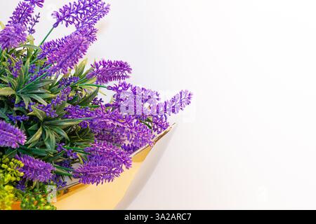 Lavender flowers bouquet composition in a golden vase against white background, spring home decor. Stock Photo