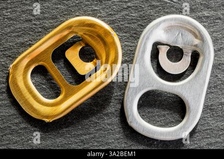 Gold and silver tabs for beverage cans, on a gray slate surface Stock Photo