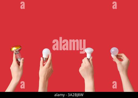 Electrician hands with different light bulbs on red background Stock Photo