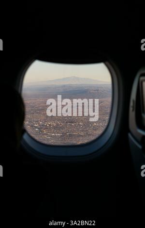 Small city through a window of a plane. Big mountain behind Stock Photo