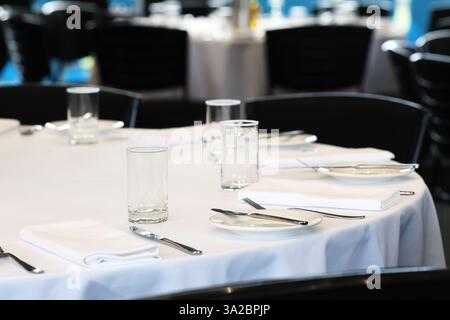 A round table with a white table cloth at a large function centre, set up ready for guests. Formal event catering and function hire. Stock Photo