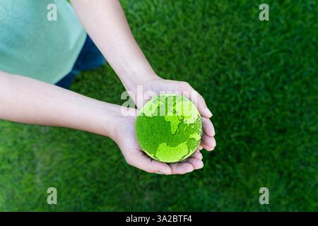 Close up of hands holding the earth on a green background. protect nature. Save Earth. concept of the environment World Earth Day. Hands holding a mos Stock Photo