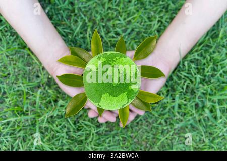 Save Earth Concept, environment World. Saving environment and environmentally sustainable. A hand holds a green globe made of grass and soil, symboliz Stock Photo