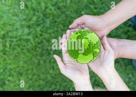 World environment day hand holding green globe on green background Environmental protection and sustainable environment Concept of cooperation to main Stock Photo