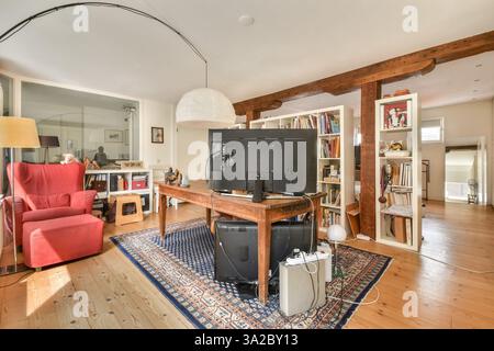 A bright and inviting home office space featuring a stylish red chair, modern desk setup, and decorative shelves filled with eclectic items. Stock Photo