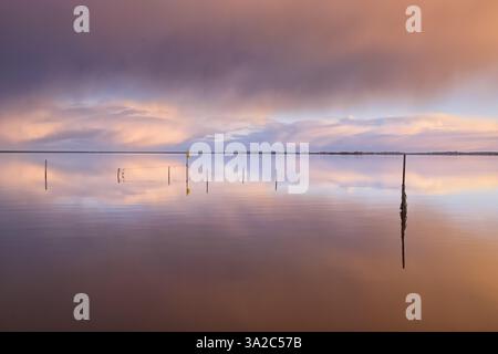 Dramatic clouds reflecting in the Lauwersmeer lake in the Netherlands with beautiful light Stock Photo