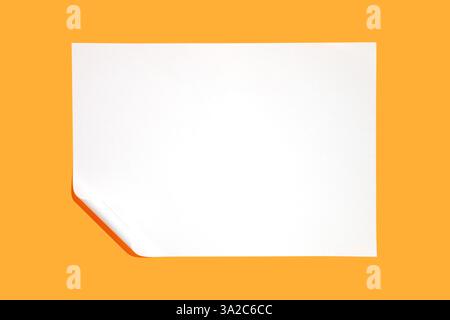 Minimalist composition featuring a pristine white sheet of paper with a gently curled corner, set against a vibrant yellow backdrop, offering ample co Stock Photo