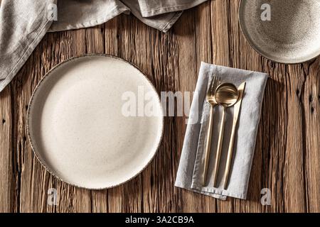 Elegant dining setup with rustic wooden table and chic tableware arranged for mealtime enjoyment. Stock Photo