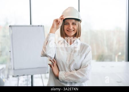 Young woman architect in hard hat is in office. Stock Photo