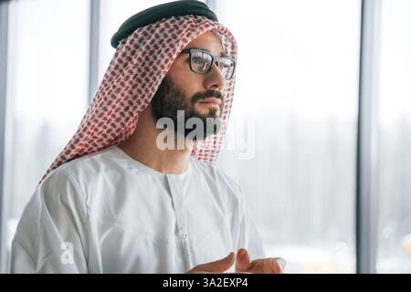 In glasses. Successful Muslim businessman in traditional outfit in his office. Stock Photo