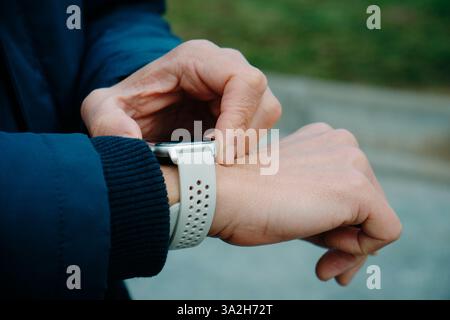 closeup of a man activating his smartwatch on the street, on a winter day Stock Photo