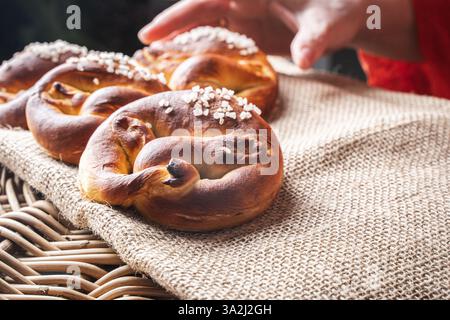 A woman's hand in out-of-focus reaches for a pretzel on a canvas on a wicker basket. Selected focus. High quality photo Stock Photo