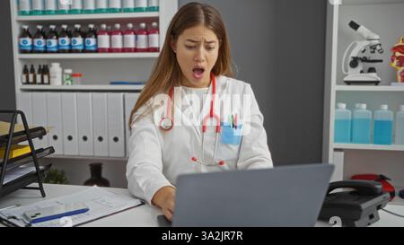 Woman doctor surprised looking at laptop in clinic with stethoscope documents and laboratory tools on shelves reflecting medical professional environm Stock Photo