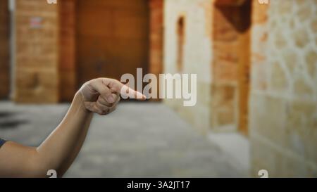 Man pointing hand outdoors on a city street set against a backdrop of aged stone buildings. Stock Photo