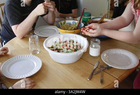 May 19, 2014 - Everett, WA, USA - Riitta Edwards, 11, adds radishes to the side salad as her siblings, Ellie Edwards, 6, from left, Nate Powell, 17 and Noah Powell, 15, wait to eat dinner with their mother Charity Edwards on Monday, May 19, 2014, in Everett, Wash. Sen. Patty Murray (D-WA) proposed legislation Wednesday, May 21, 2014, to give poor families $150 per child to spend on food during the summer months. (Credit Image: © Kevin Fujii/MCT/ZUMAPRESS.com) Stock Photo