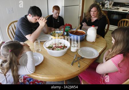 May 19, 2014 - Everett, WA, USA - Charity Edwards, clockwise from upper right, Riitta Edwards, 11, Ellie Edwards 6, Nate Powell, 17, and Noah Powell, 15, pray before their dinner on Monday, May 19, 2014, in Everett, Wash. Sen. Patty Murray (D-WA) proposed legislation Wednesday, May 21, 2014, to give poor families $150 per child to spend on food during the summer months. (Credit Image: © Kevin Fujii/MCT/ZUMAPRESS.com) Stock Photo