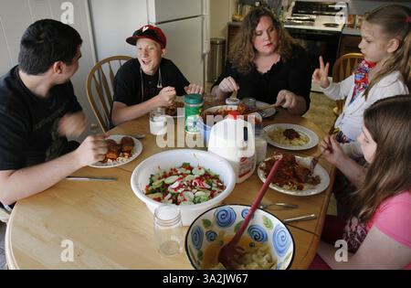 May 19, 2014 - Everett, WA, USA - Charity Edwards, clockwise from upper middle puts two meatballs on six-year-old Ellie Edwards plate as Riitta Edwards, 11, Nate Powell, 17, and Noah Powell, 15, eat their dinner on Monday, May 19, 2014, in Everett, Wash. Sen. Patty Murray (D-WA) proposed legislation Wednesday, May 21, 2014, to give poor families $150 per child to spend on food during the summer months. (Credit Image: © Kevin Fujii/MCT/ZUMAPRESS.com) Stock Photo