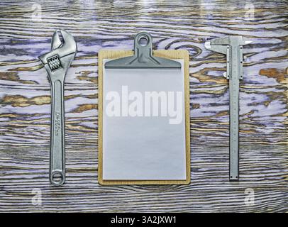 Vernier caliper adjustable spanner clipboard on wooden board Stock Photo