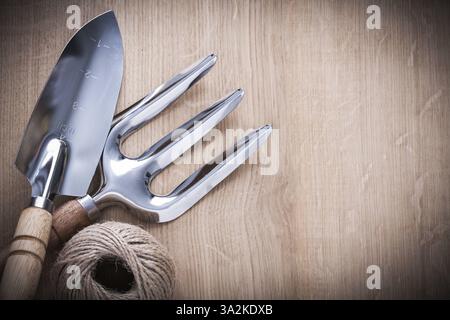 Stainless hand shovel trowel fork and hank of twine on vintage wooden board gardening concept Stock Photo