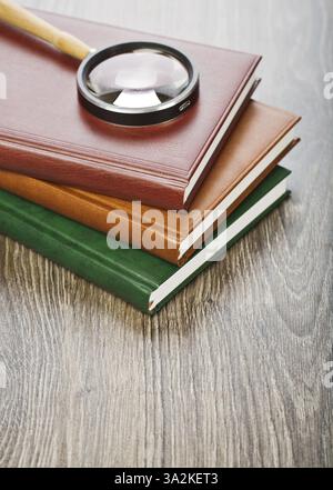Three notebooks and magnifier Stock Photo