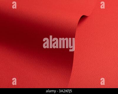 Bright red paper background with a matte texture and rough grain. Vibrant hues create an elegant, luxurious abstract design with a perforated, punched Stock Photo