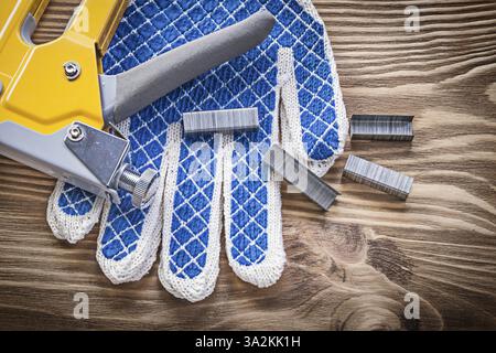 Stapler gun safety gloves staples on wooden board Stock Photo