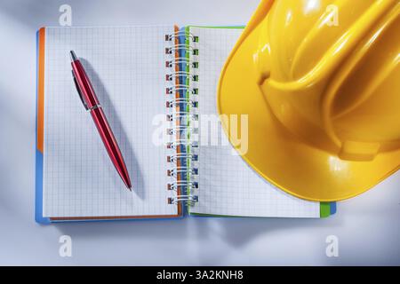 Safety hard hat checked notepad pen on white background Stock Photo