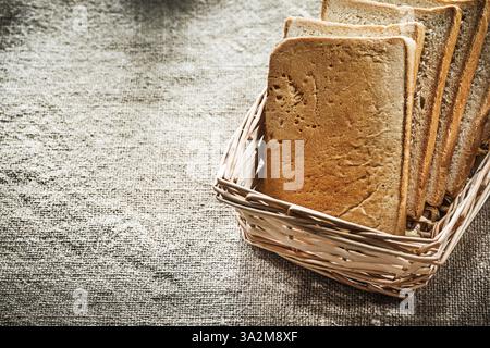 Wicker basket sliced bread on vintage sacking background Stock Photo