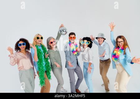 Group of smiling diverse colleagues having fun in colorful party outfits, enjoying a joyful and professional atmosphere Stock Photo