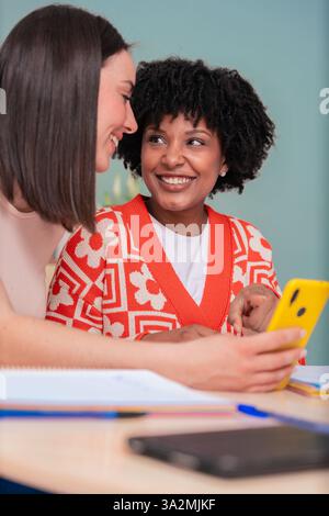 Happy African American and Caucasian students looking at smartphone together Stock Photo