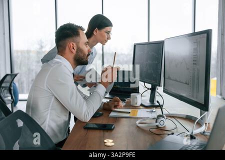 Working on a project together. Two employees are in the office. Stock Photo