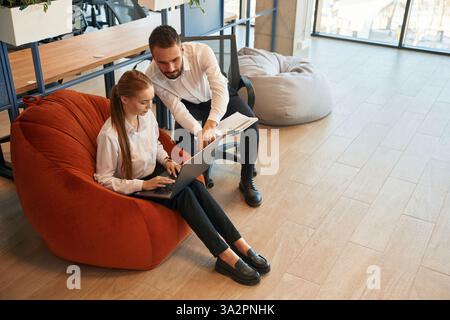 Sharing new ideas, showing information in laptop. Man and woman employees are working in the office. Stock Photo