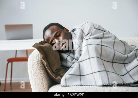 Lying down on the sofa. Sick black man is at home. Stock Photo