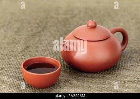 Traditional Chinese clay brick-colored teapot and cups with tea on a table. Stock Photo