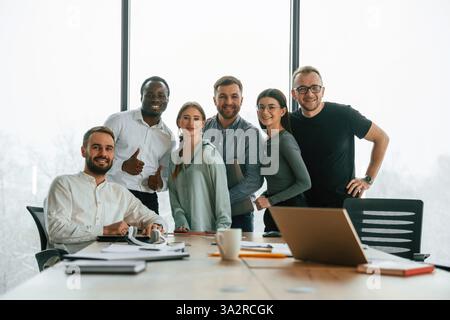 Posing for the camera. Team of office workers are together indoors. Stock Photo