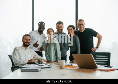 Front view, smiling, posing for the camera. Team of office workers are together indoors. Stock Photo