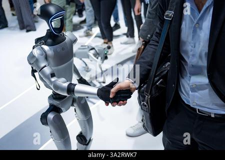 A humanoid robot by the company Unitree is seen shaking hands with people in a handshake. Concept of human and robots interaction and robotics enginee Stock Photo