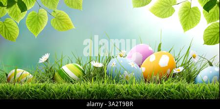 Six painted easter eggs celebrating a Happy Easter on a spring day with a green grass meadow, bright sunlight, tree leaves and a cool background Stock Photo