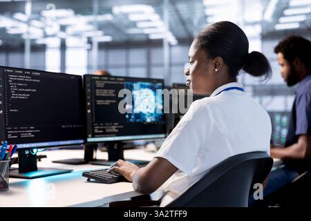 Server farm IT expert doing AI research, creating and implementing algorithms using neural networks. African american woman in data center using artificial intelligence computational models Stock Photo
