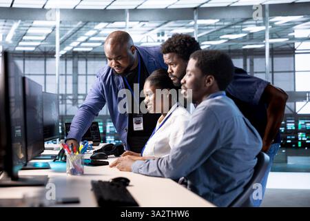 Group of technicians doing brainstorming, reconfiguring server farm to optimize it for data processing requirements. Employees working together to ensure data center equipment operates efficiently Stock Photo