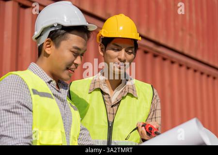 Engineering Collaboration. Two young engineers discussing logistics plans outdoors. Stock Photo