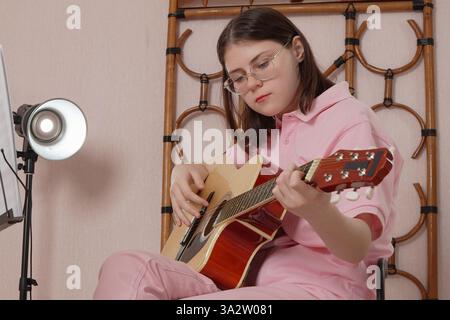 Woman guitarist is performing strumming style of six string acoustic guitar, utilizing six string acoustic instrument. Performance is taking place in Stock Photo