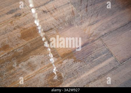 Water is cascading down onto a wooden floor, creating ripples Stock Photo